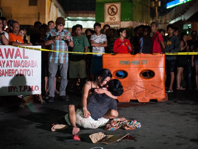 A woman embraces her dead husband, a suspected drug dealer, after he was shot by motorcycle riding vigilantes in Manila. Picture: Getty Images