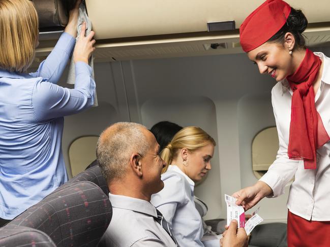 Air stewardess check ticket airplane cabin smiling