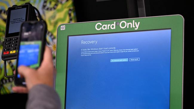 A man takes a picture of the blue screen at self-checkout terminals of a supermarket in Sydney on Friday. Picture: AFP