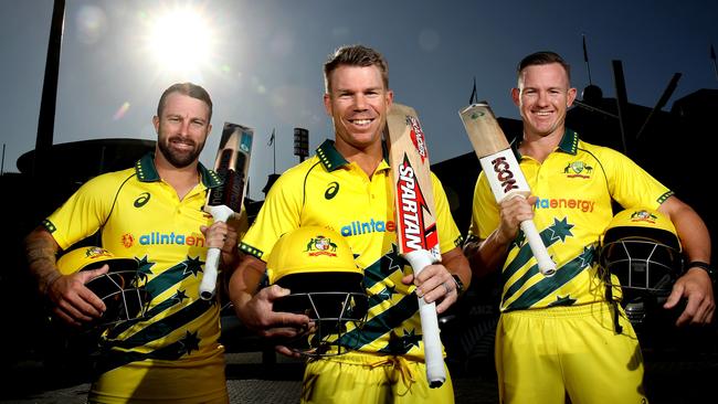 Australian players Matthew Wade, David Warner and D’Arcy Short in their team uniforms … and with the yellow helmets they’ll wear while batting against New Zealand at the SCG tomorrow. Picture: Phil Hillyard