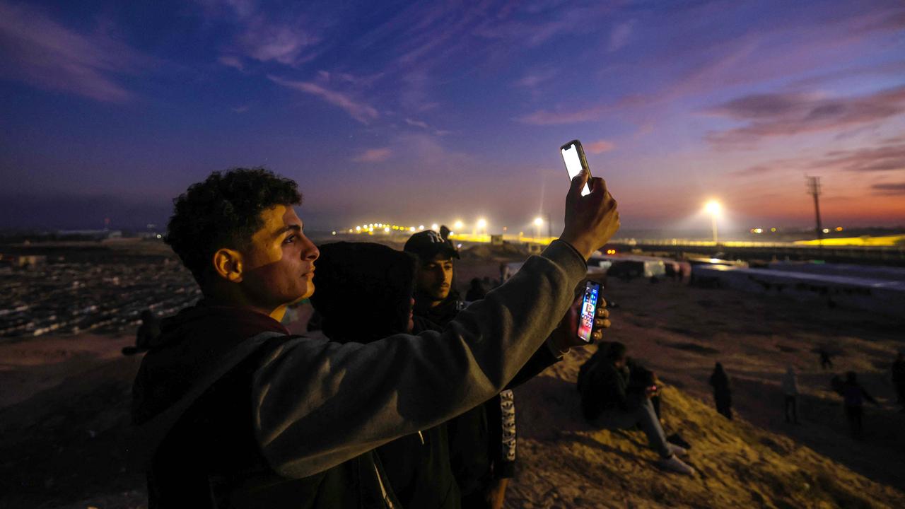 Displaced Palestinians using eSIM cards attempt to get a signal in order to contact their loved ones on a hill in Rafah, on the southern Gaza Strip. Picture: AFP