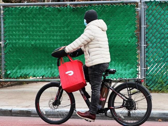 (FILES) In this file photo a Doordash delivery person rides their bike on Church Avenue in the Flatbush neighborhood of Brooklyn on December 04, 2020 in New York City. - Airbnb and DoorDash make their stock market debut this week as part of a 