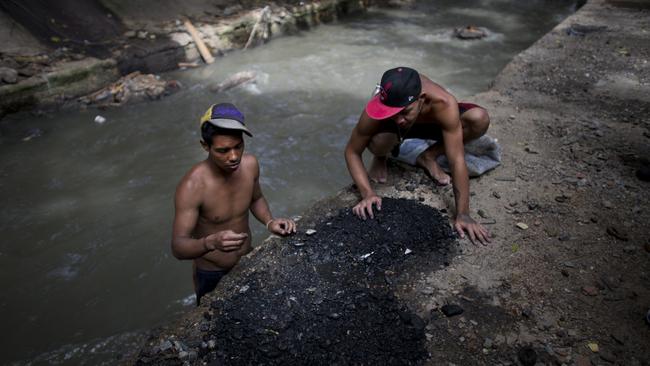 Men sort through the debris they pulled up from the bottom of the polluted Guaire River, in search of pieces of gold and anything of value to sell in Caracas, Venezuela. Picture: AP/Ariana Cubillos