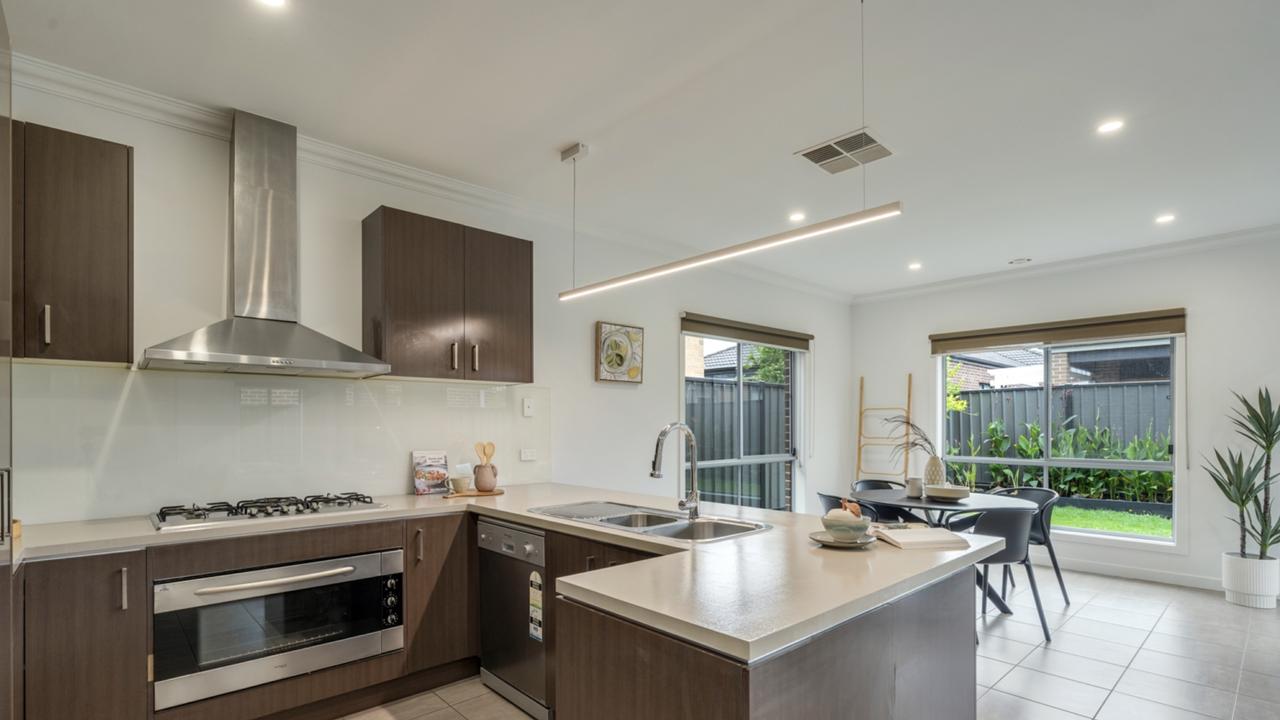Sleek stainless steel appliances and an island bench anchor the modern kitchen at 40 Kelway St.