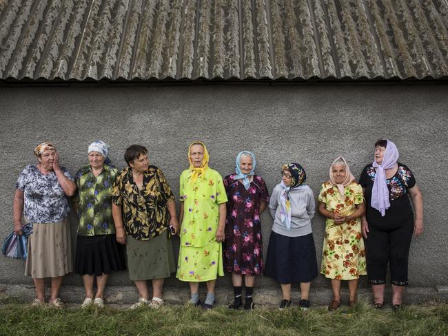 A group of elderly women from a nearby village shelter from the rain after visiting the crash site of Malaysia Airlines flight MH17 in Grabove yesterday. Picture: Rob Stothard