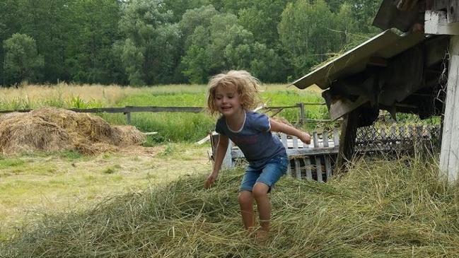 Enjoying the simple, peaceful life, Nadia Renkas plays in the hay at a farmhouse during a family holiday to Ukraine.