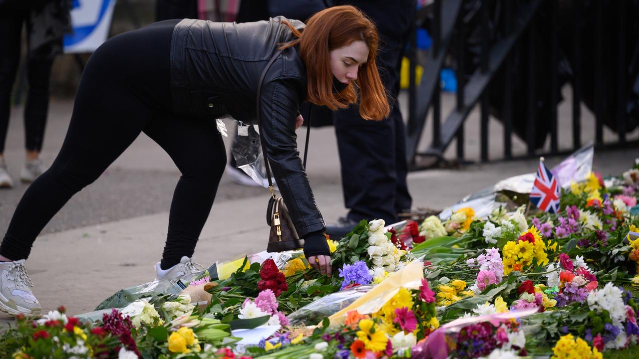 A woman adds a bunch of flowers to the floral tributes outside Windsor Castle following the death of Prince Philip, on April 9. Picture: Leon Neal/Getty Images