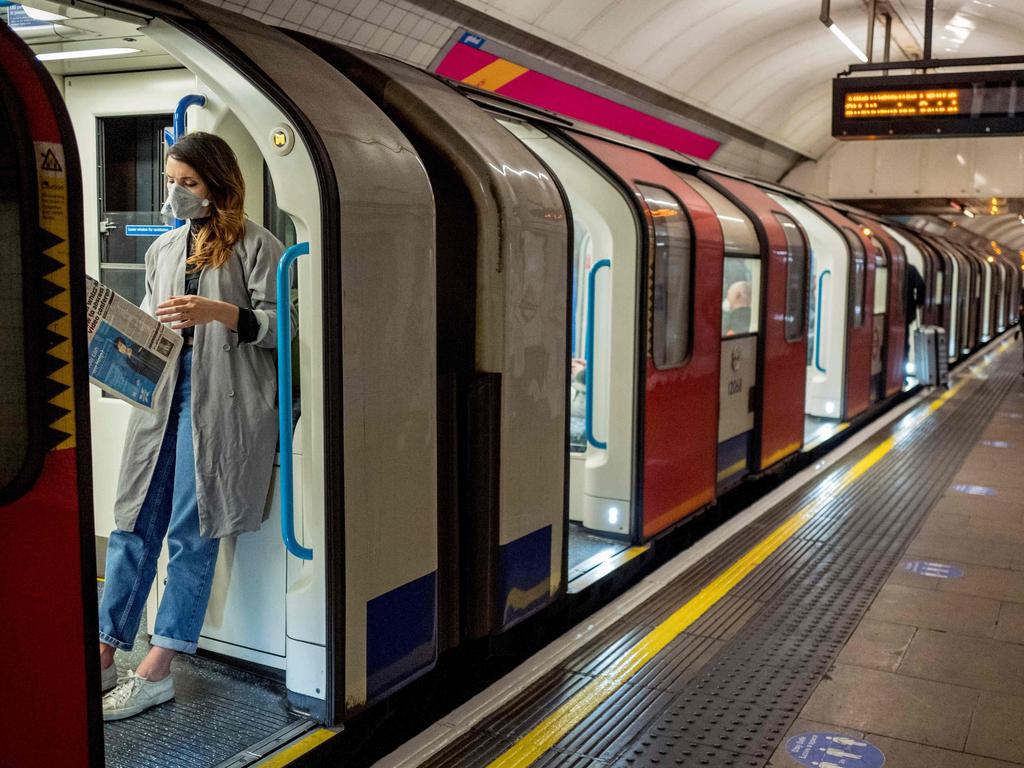 A mask-clad woman stands on a virtually empty train in London. Lockdown measures could be extended until 2021. Picture: AFP