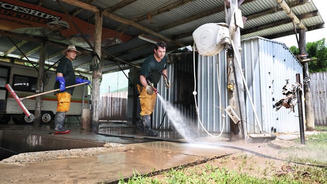 Rural Fire Brigade members Mark Schermer and Tyson Pringle hose out a flooded shed in the backyard of a Gregory Street home in Cardwell. Picture: Brendan Radke