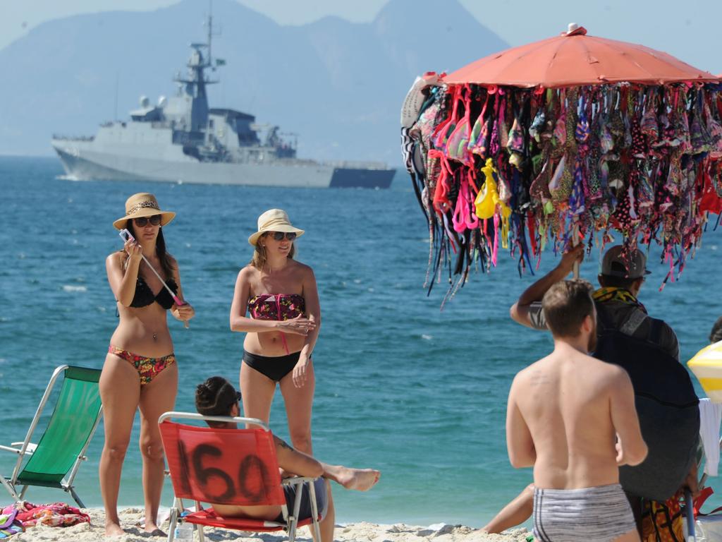 People enjoy the day at Copacabana beach as a ship patrols the coast enhancing security ahead of the Rio 2016 Olympic Games, in Rio de Janeiro, Brazil, on July 24, 2016. Picture: AFP PHOTO / TASSO MARCELO