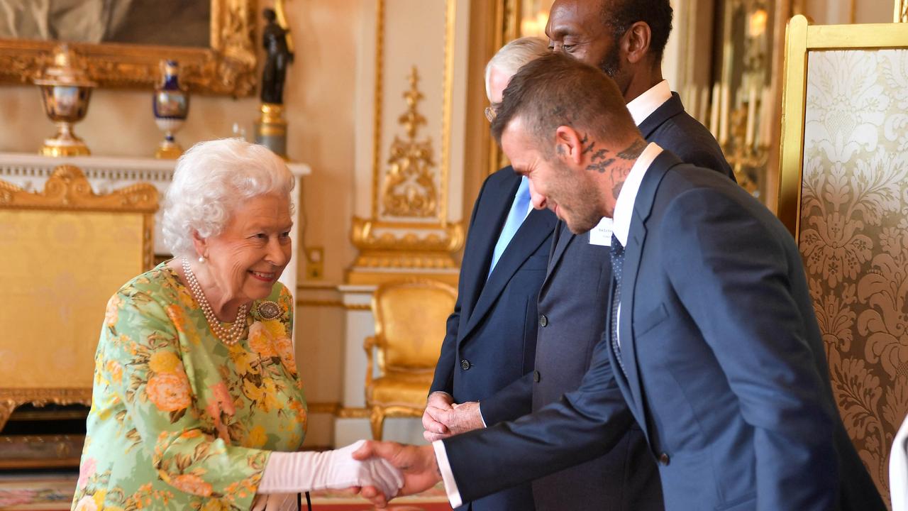 Britain's Queen Elizabeth II greets former England international David Beckham. Photo by John Stillwell / POOL / AFP.