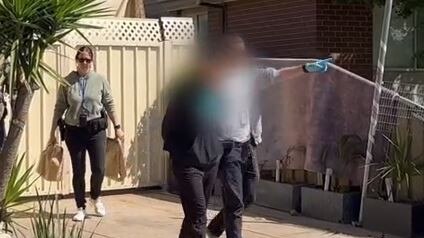 Police executing a search warrant lead an arrested man from a property. Picture: VicPol