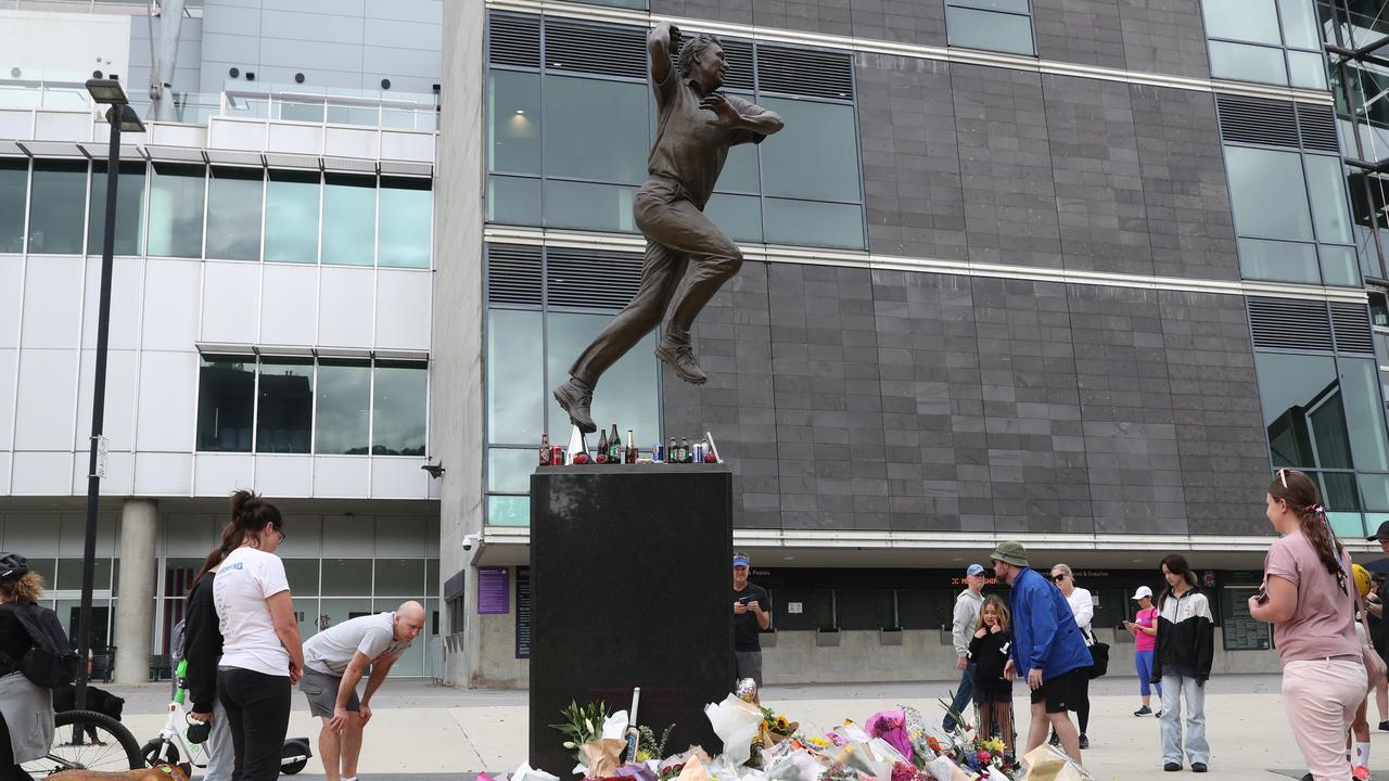 People lay flowers and other items at the statue of Shane Warne at the Melbourne Cricket Ground. NCA NewsWire / David Crosling