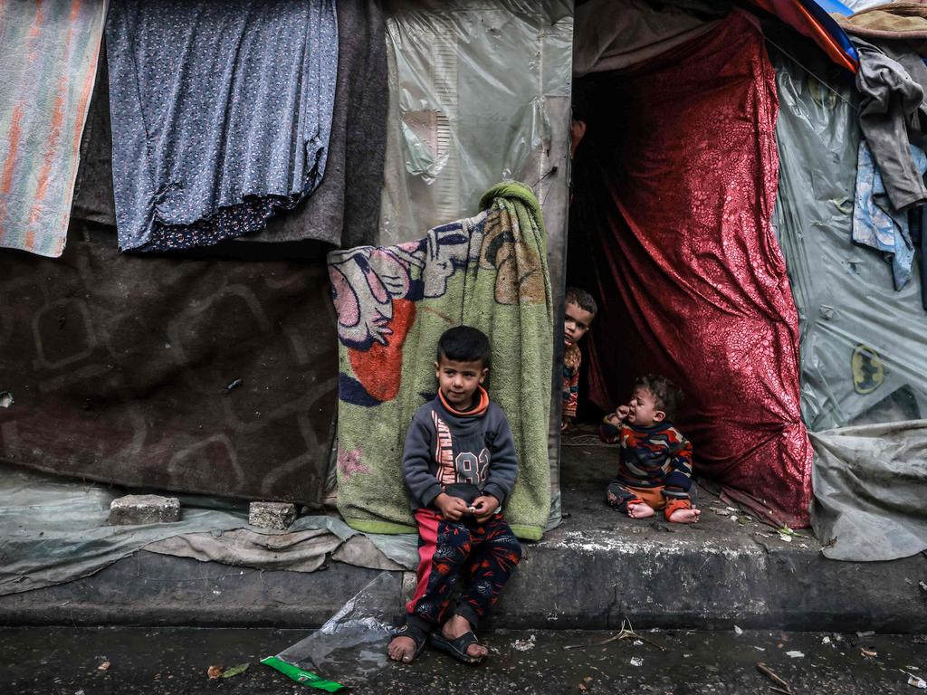 Displaced Palestinian children wait in front of their makeshift tent at a camp beside a street in Rafah. Picture: AFP