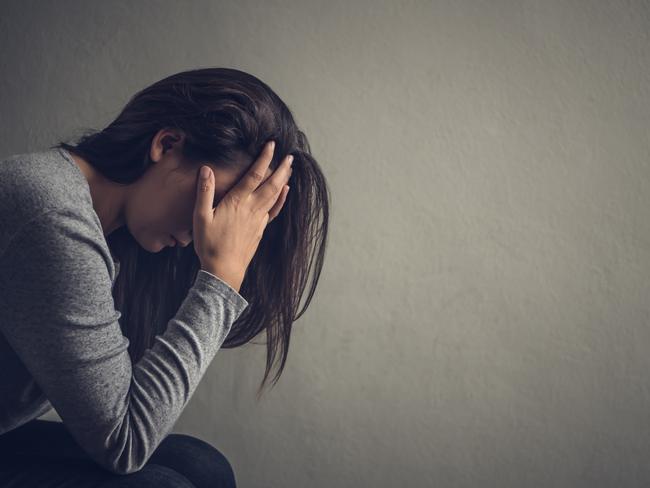 Depressed woman sitting on a chair in dark room at home. Lonly , sad, emotion concept.