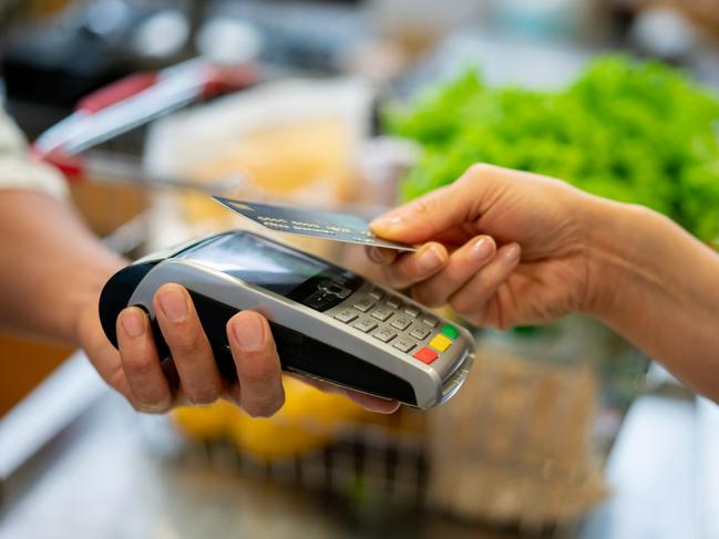 Close up of unrecognizable customer doing a contactless payment at the supermarket **DESIGN ON CREDI CARD WAS MADE FROM SCRATCH BY US**