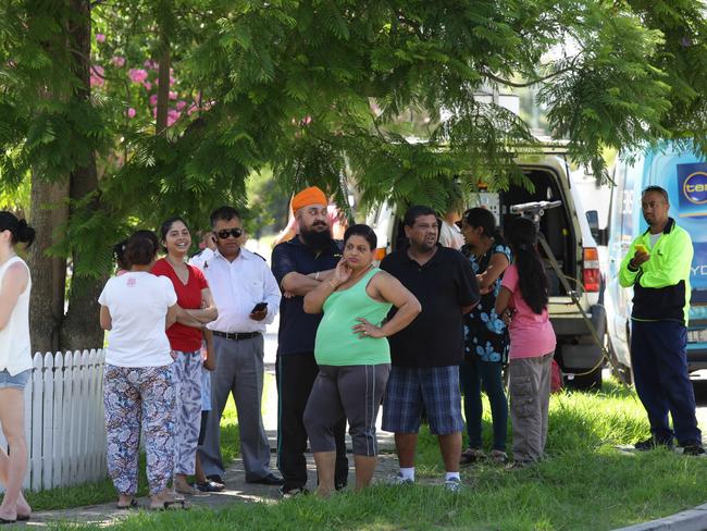 Shocked neighbours watch on as police investigate the shooting.