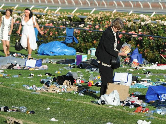 A woman packs up her bread amid a mostly deserted field at Flemington after a successful Derby Day. Picture: AAP.