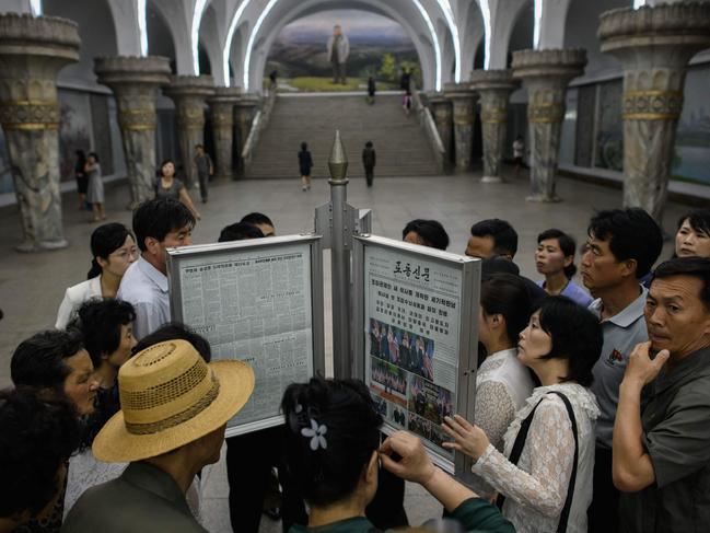 Commuters gather round the latest copy of the Rodong Sinmun newspaper showing images of North Korean leader Kim Jong Un meeting with US president Donald Trump during their summit in Singapore, at a news stand on a subway platform of the Pyongyang metro on June 13, 2018. Donald Trump accepted an invitation from Kim Jong Un to visit North Korea during their historic summit, Pyongyang state media reported on June 13, as the US president said the world had jumped back from the brink of 