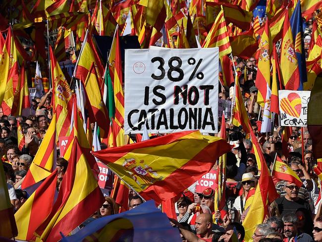 Protesters wave Spanish and Catalan Senyera flag while holding a sign reading "38 per cent is not Catalonia" in reference to a referendum voter turnout. Picture: Lluis Gene/AFP