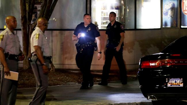 A police officer uses a flashlight while searching the area. Picture: AP