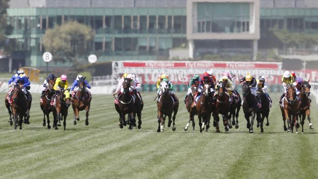 The Melbourne Cup field makes its way down the Flemington straight for the first time.