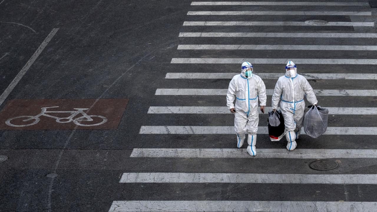 Epidemic control workers walk across a road in an area with communities in lockdown on December 1, 2022 in Beijing, China. Picture: Kevin Frayer/Getty Images