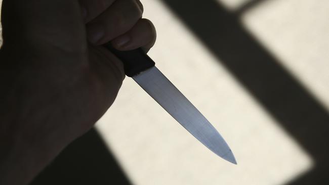 A hand holding a knife in shadow. This image can be used to represent stabbing or murder.