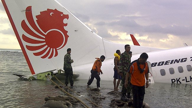 In this photo released by Indonesia's National Rescue Team, rescuers stand near the wreckage of a crashed Lion Air plane in Bali, Indonesia.