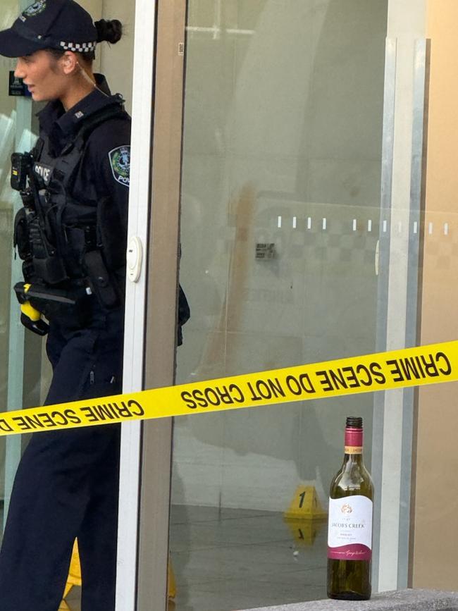 An evidence marker, empty wine bottle and what appears to be blood on the wall at the scene. Picture: Emma Brasier