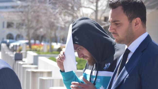 Domenico Luca Costanzo (centre) leaving court in a blue hoodie with his legal team.