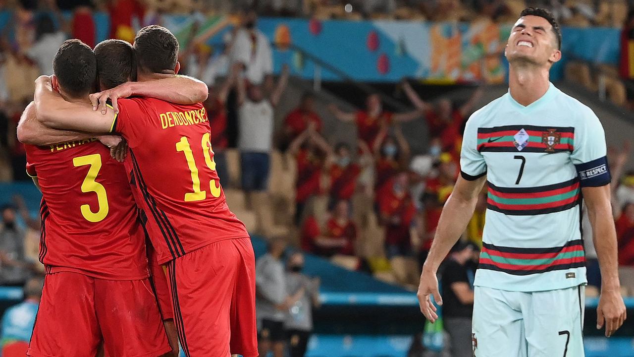 TOPSHOT - Portugal's forward Cristiano Ronaldo (R) reacts as Belgium's players celebrate their victory at the end of the UEFA EURO 2020 round of 16 football match between Belgium and Portugal at La Cartuja Stadium in Seville on June 27, 2021. (Photo by LLUIS GENE / POOL / AFP)