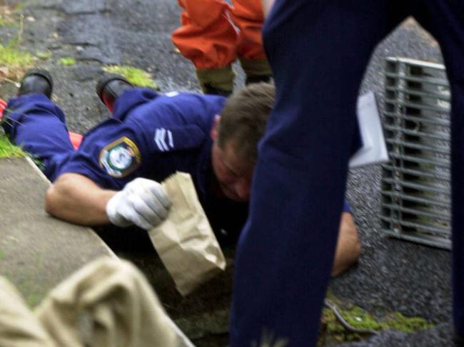 A police officer photographs evidence in drain near the victim's house in 2001.