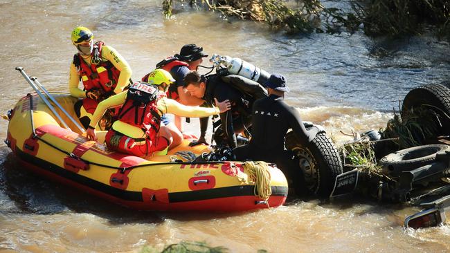 Queensland Police Divers and Queensland Fire Swift Water Rescue Team members search the vehicle was found submerged and upside down in Canungra Creek. Picture: Scott Powick