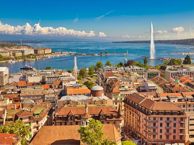 Geneva skyline cityscape, French-Swiss in Switzerland. Aerial view of Jet d'eau fountain, Lake Leman, bay and harbor from the bell tower of Saint-Pierre Cathedral. Sunny day blue sky.