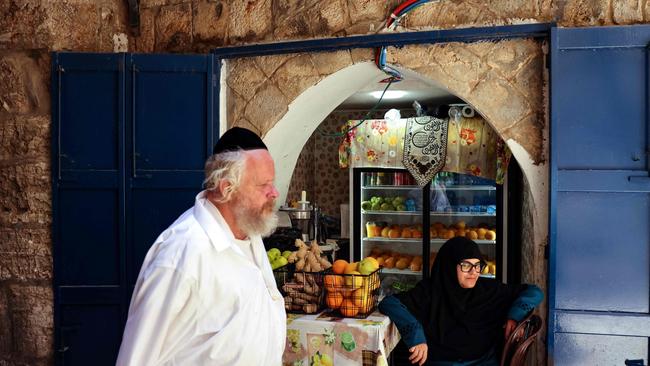 An ultra-Orthodox Jewish man walks past a Palestinian woman sitting in front of a fresh juice shop, in the Old City of Jerusalem on August 9, 2024. Picture: AFP