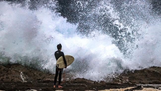 A surfer eyes off the rough conditions. Authorities have urged people to stay out of the water due to the east coast low. Picture: Nigel Hallett