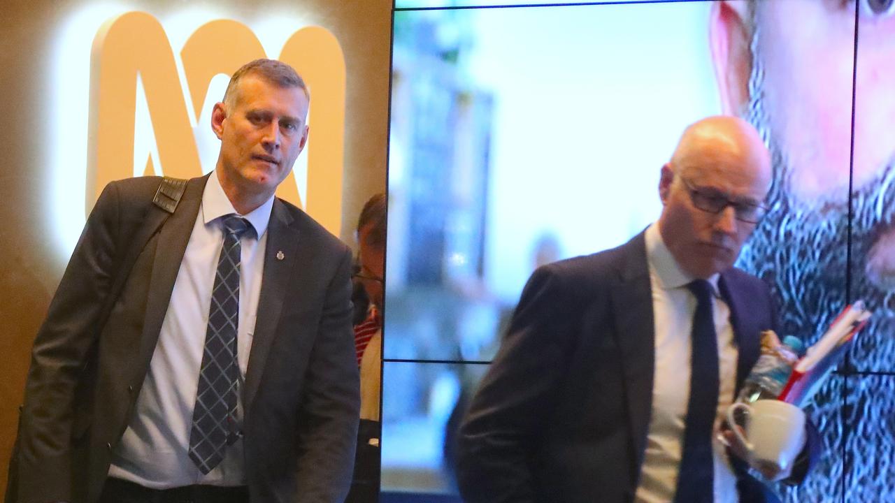 ABC News executive director John Lyons (right) is followed by an Australian Federal Police officer as they walk out of the main entrance to the ABC building in Ultimo, Sydney, on Wednesday, June 5. Picture: David Gray/AAP.