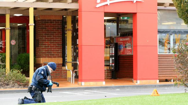 A police officer photographs evidence on the scene. Picture: Mark Stewart