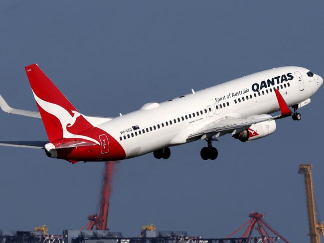 This picture taken on December 6, 2023 shows a Qantas Airways Boeing 737-800 passenger aircraft taking off at Sydneyâs Kingsford Smith international airport in front of a container ship berthed at the Port Botany container terminal. (Photo by DAVID GRAY / AFP)