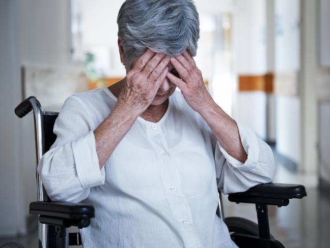 Shot of a senior woman in a wheelchair sitting with her hands over her eyes