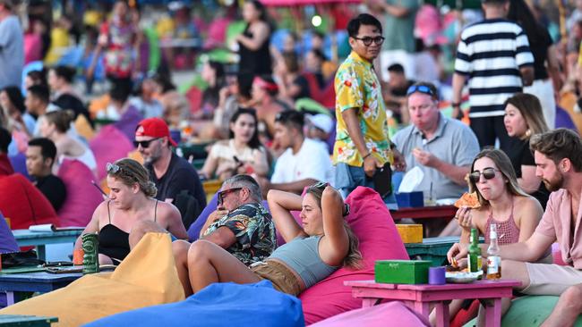 Foreign tourists relax on the Kuta Beach near Denpasar on Indonesia's resort island of Bali on November 18, 2023. (Photo by SONNY TUMBELAKA / AFP)