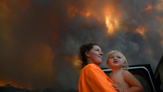 Sharnie Moren and her 18-month-old daughter Charlotte look on as thick smoke rises from bushfires near Nana Glen, north of Coffs Harbour on Tuesday. Picture: AAP