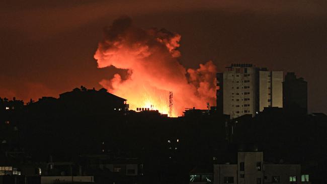 Fire and smoke rise above buildings in Gaza City during an Israeli air strike early on Friday. Picture: Mahmud Hams/ AFP