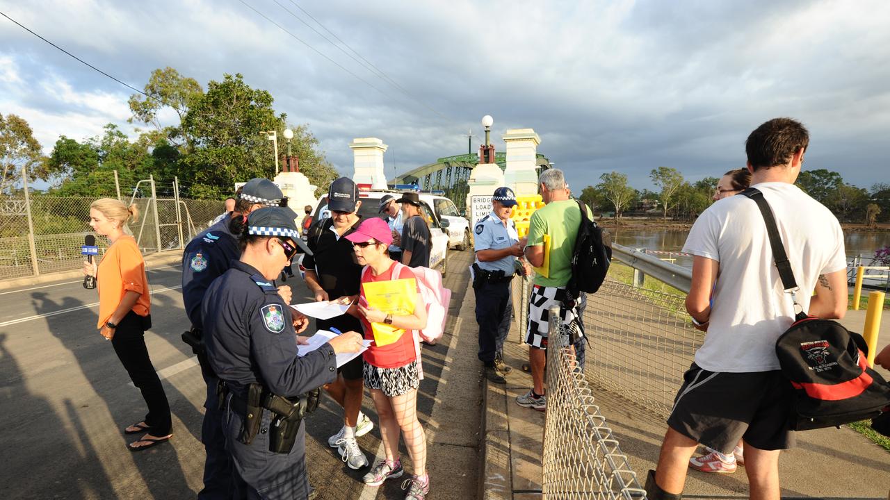 Police check residents' identification as they line up to cross the Burnett Bridge into the exclusion zone to inspect their flood damaged homes, North Bundaberg, Saturday, Feb. 2, 2013. Residents of the hardest hit suburb in Queensland's flood crisis have begun the heartbreaking journey of returning home to assess damage after police opened the Burnett Bridge to north Bundaberg residents at 6am. (AAP Image/Paul Beutel) NO ARCHIVING