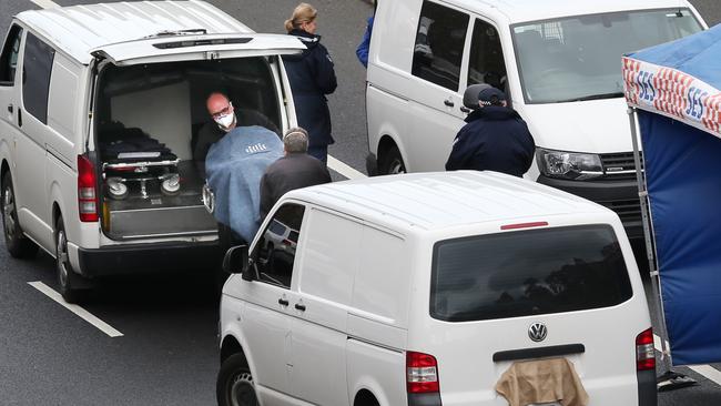 Police load a body into a coroner’s van. Picture: David Crosling