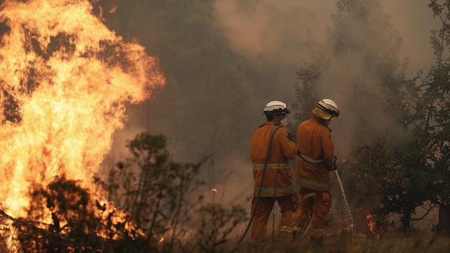 Tasmania Fire Service personnel put out a spot fire threatening a home on Donnelleys Rd, Geeveston. Picture: LUKE BOWDEN