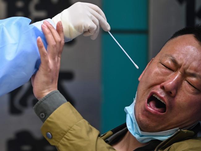 (FILES) In this file photo taken on April 16, 2020 A man being tested for the COVID-19 novel coronavirus reacts as a medical worker takes a swab sample in Wuhan in China's central Hubei province on April 16, 2020. - the Guardian picture desk has chosen the AFP photojournalist Hector Retamal as agency photographer of the year 2020 for his coverage of the novel coronavirus Covid-19 pandemic in Wuhan, China. (Photo by Hector RETAMAL / AFP)