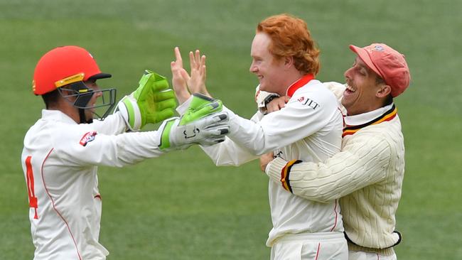 Lloyd Pope of the Redbacks celebrates with Harry Nielsen and Jake Lehmann after   trapping Steve O'Keefe of the Blues for his maiden JLT Sheffield Shield wicket. Picture: AAP Image/David Mariuz