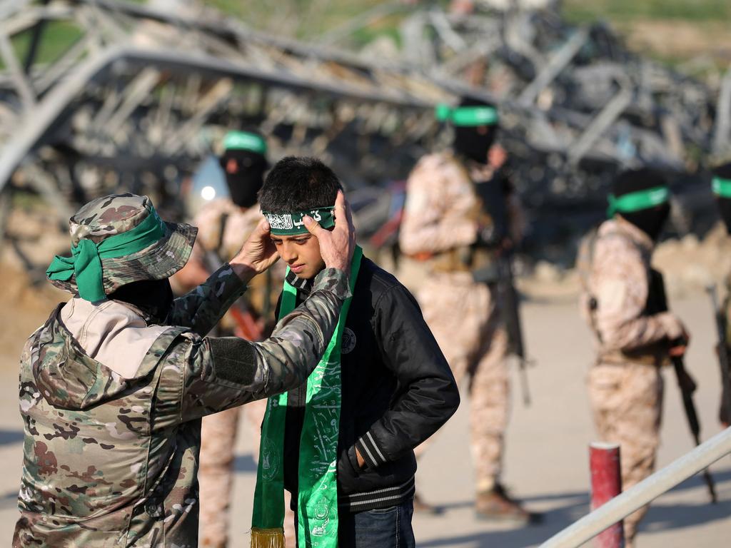 A Palestinian Hamas fighter fixes a green band around a child's head near the family home of slain Hamas leader Yahya Sinwar, ahead of the handover of Israeli and Thai hostages to a Red Cross team in Khan Yunis. Picture: AFP